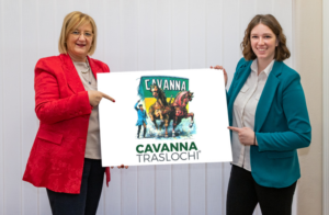 Loretta Lazzarini e Ilaria Mauri del Centro Servizi Immobiliari tengono in mano un cartello con il logo Cavanna Traslochi Milano